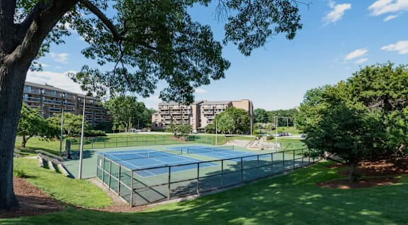 A tennis court surrounded by trees and buildings.