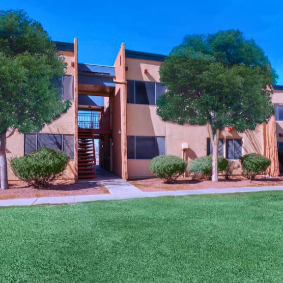 an apartment building with a lawn and trees in front of it