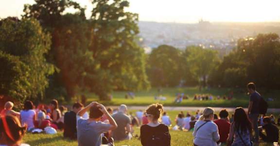 A group of people are sitting on the grass in a park.