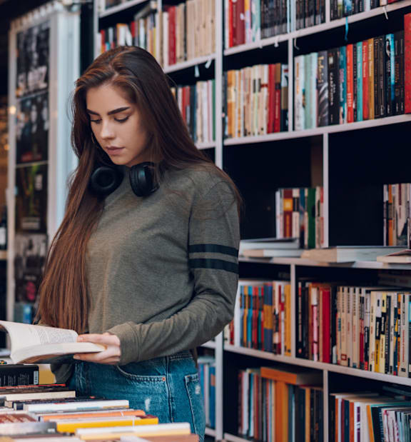 A woman is reading a book in a bookstore.
