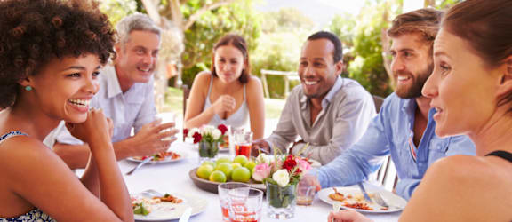 A group of people are sitting around a table enjoying a meal and drinks.