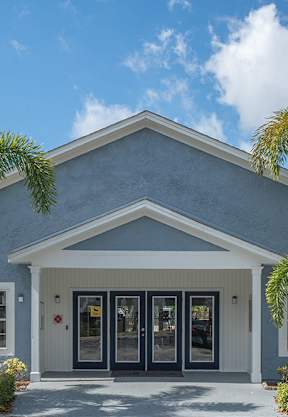 a building with palm trees and a sign in front of a garden
