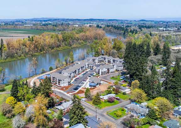 A bird's eye view of a residential area with a river and trees in the background.