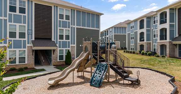 an outdoor playground with a slide in front of an apartment building