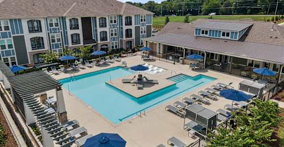 an aerial view of a swimming pool with chairs and umbrellas and a building