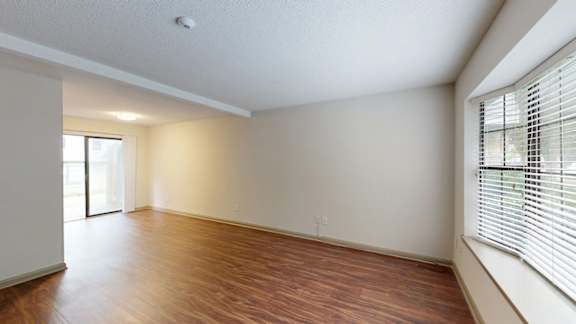 A room with wooden floors and a window with blinds.