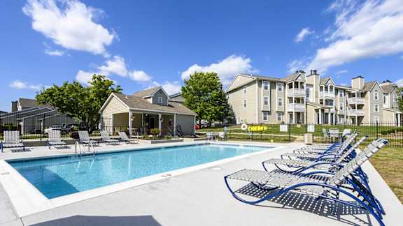 A large swimming pool surrounded by lounge chairs and umbrellas.
