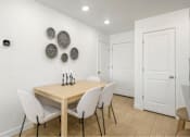 Thumbnail 4 of 10 - A dining room with a wooden table and white chairs.