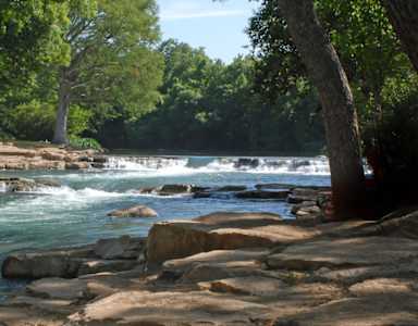 A river flows through a rocky landscape with trees on either side.
