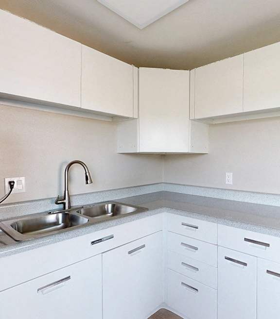 A kitchen with white cabinets and a stainless steel refrigerator.