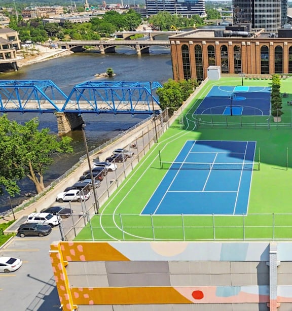 A tennis court is located on a rooftop with a river and buildings in the background.