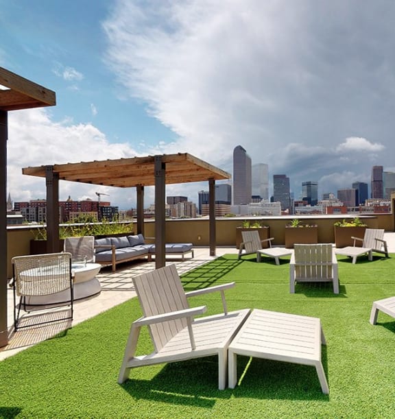 a roof top patio with lounge chairs and a view of the city