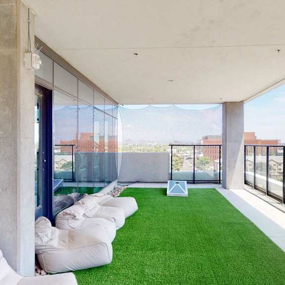 A modern balcony with white bean bags and a green lawn.