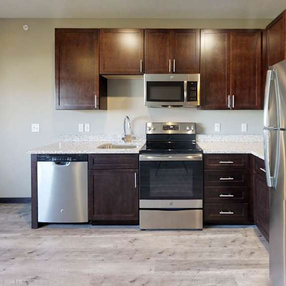 a kitchen with dark wooden cabinets, granite countertops, and stainless steel appliances