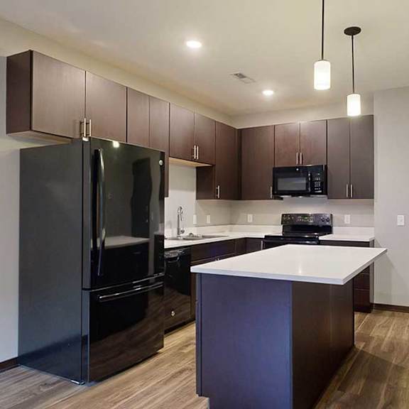a kitchen with dark cabinets, black appliances, and granite countertops