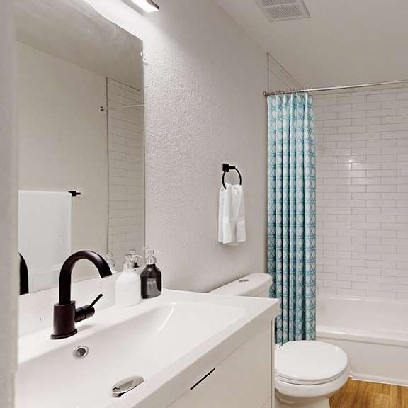 A white bathroom with a toilet, sink, and shower.