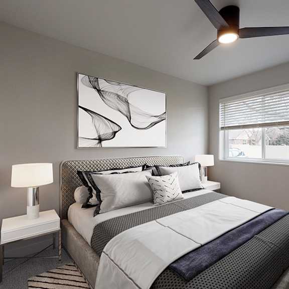 A bedroom with a large bed and a ceiling fan.