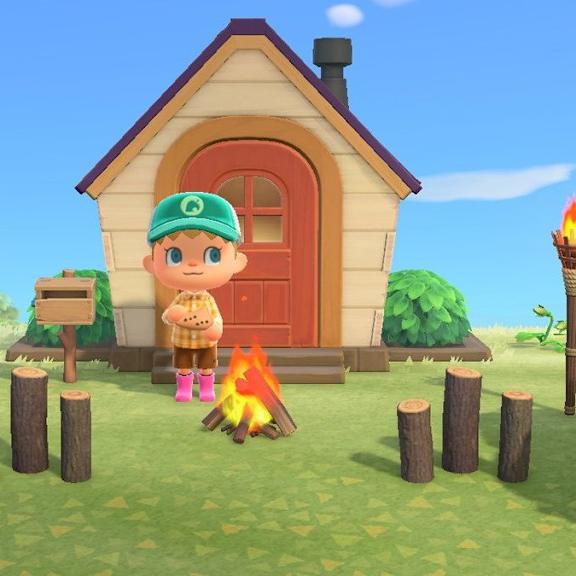 A character in a green hat stands in front of a house with a fire burning in front of it.