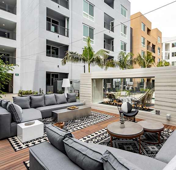 A modern outdoor seating area with grey couches and a wooden deck. at Baker Block, Costa Mesa, CA, 92626