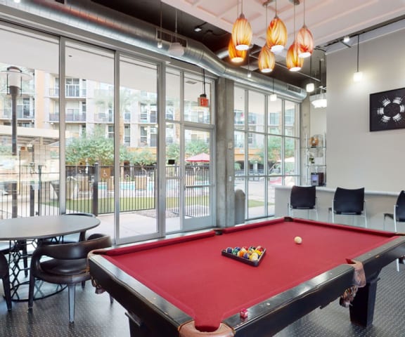 a red pool table in a room with large windows