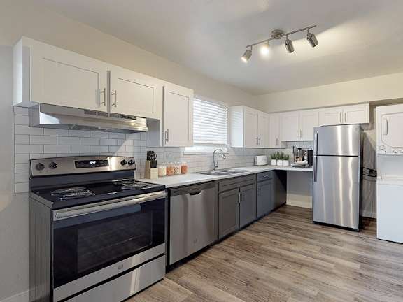 A modern kitchen with stainless steel appliances and wooden floors.