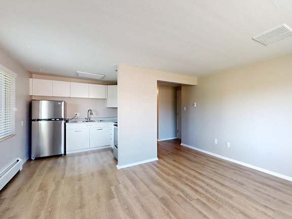 A kitchen with white cabinets and a stainless steel refrigerator.
