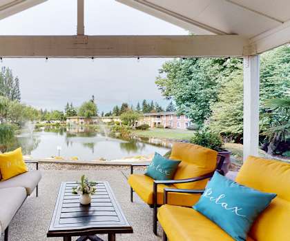 A patio with a table and chairs overlooking a pond.