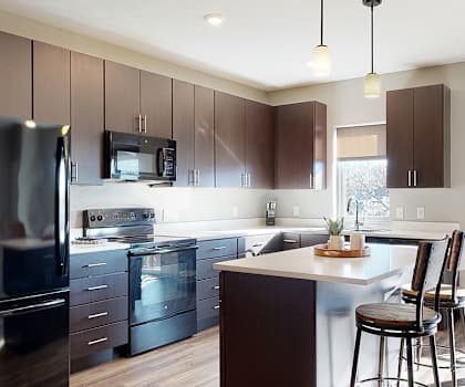 a large kitchen with stainless steel appliances and dark brown wooden cabinets