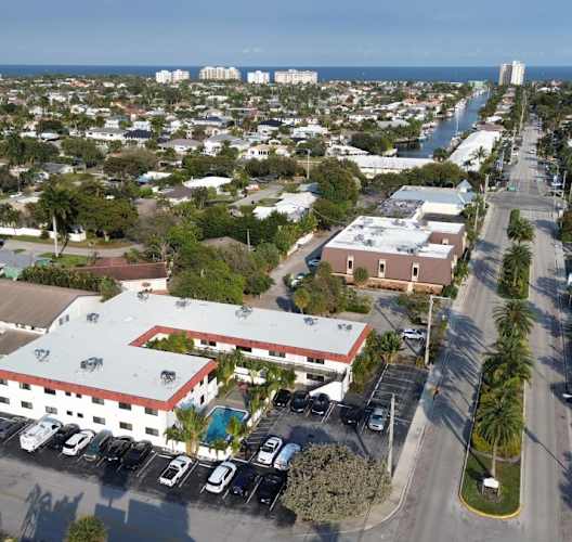 A parking lot with a white building with a red roof in the middle of a street.