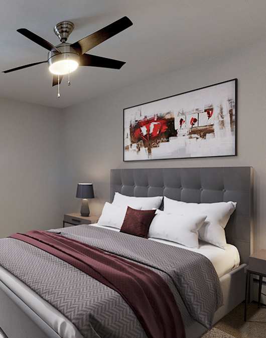 A bedroom with a large bed and a ceiling fan.