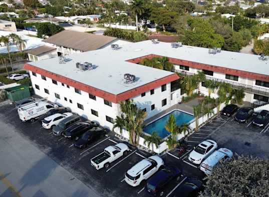 A large white building with a red roof and a parking lot in front.