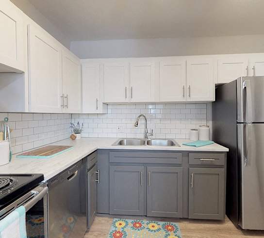 A kitchen with a stove, sink, and refrigerator.