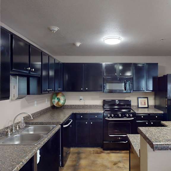 A kitchen with black cabinets and granite counter tops at Citifront Apartment Homes.