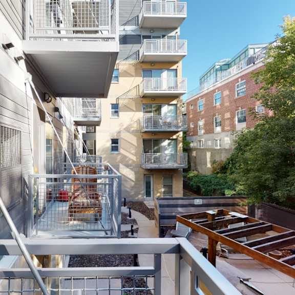 The view from the balconies of the other metal and concrete balconies on the side of the gray apartment building overlooking the patio of Vue Apartment Homes. 