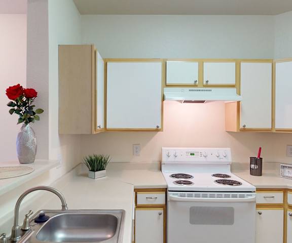 A kitchen with white appliances and counters at Citifront Apartments. 