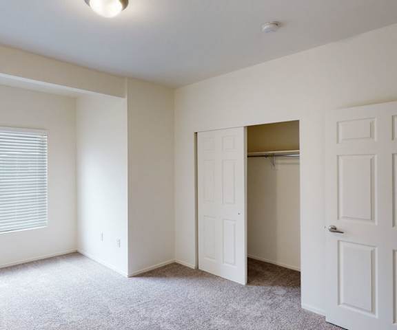 An empty bedroom with a window and closet at Citifront Apartments. 