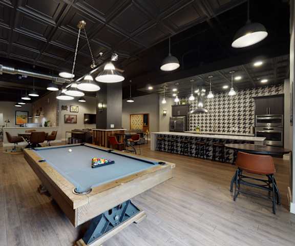 A resident lounge with tables, chairs, and a pool table at Lofts at Watters Creek Apartments. 