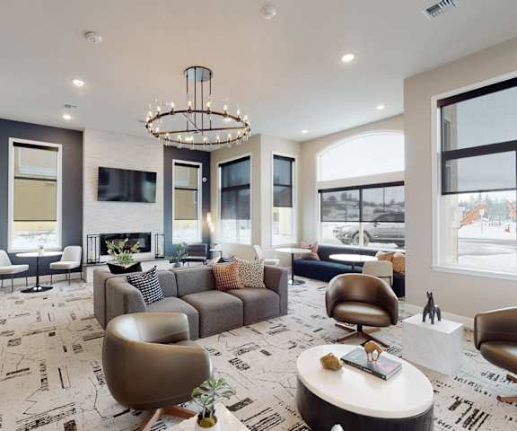 The neutral-colored front office and resident lounge with couches, a TV, fireplace, windows, and a coffee table at LIVEasy Apartments. 