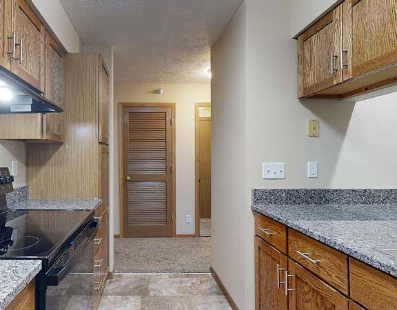 a galley kitchen with granite countertops and wooden cabinets