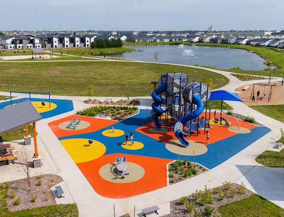 A playground with a blue and yellow slide and a red and white slide.