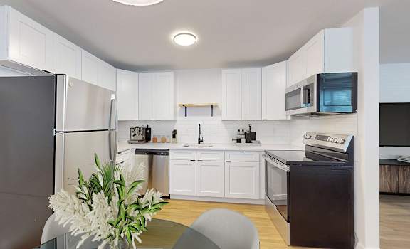 A modern kitchen with white cabinets and stainless steel appliances.
