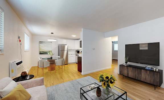 A modern living room with a grey sofa, a glass coffee table, and a television.