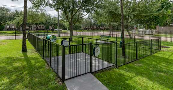 a wrought iron fence around a playground in a park