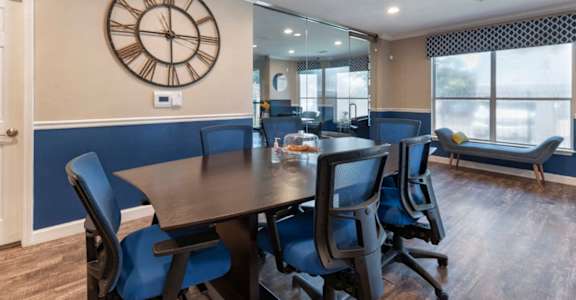 a conference room with a table and chairs and a clock on the wall