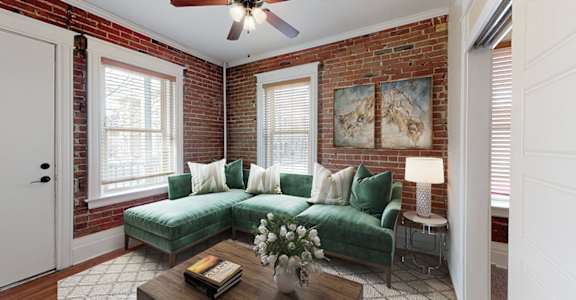 A living room with a green couch and a ceiling fan.
