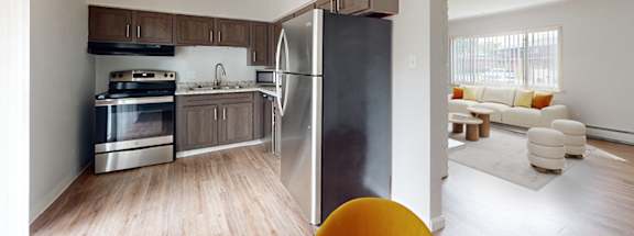 A kitchen with a refrigerator, oven, and sink.