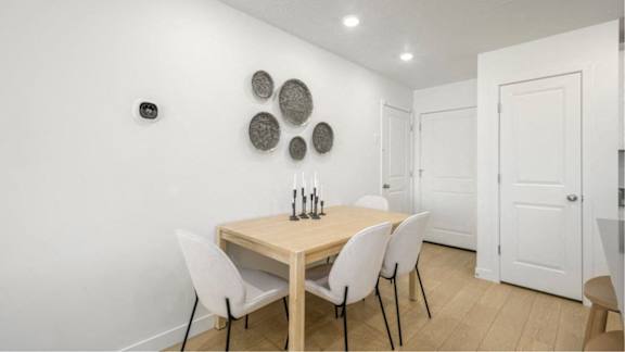 A dining room with a wooden table and white chairs.