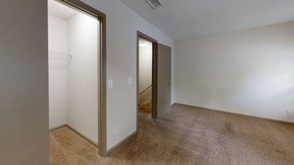 A room with a carpeted floor and two open doors.