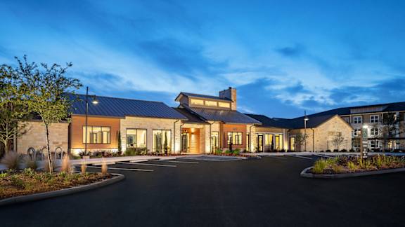 Inviting apartment community entrance with upscale architecture, professional landscaping, and a well-lit arrival experience.