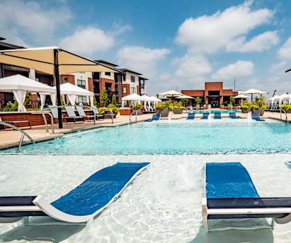 A large outdoor pool with sun loungers and umbrellas.